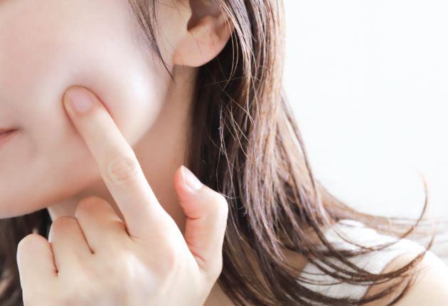 頬に指で触れる女性